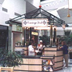 Custom concierge kiosk in retail center includes desk and services